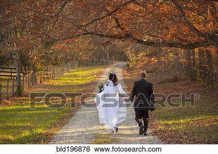 Stock Photo - Bride and groom walking on path. Fotosearch