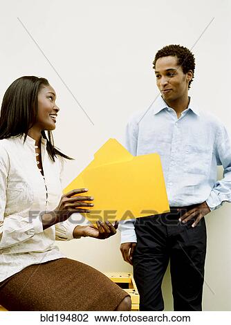 Stock Image - Business people discussing file folders. Fotosearch