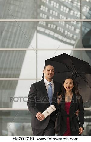 Business people standing together with umbrella View Large Photo Image Stock Photo - Business people standing together with umbrella. Fotosearch