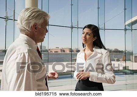 Business people talking in office lobby with glass wall View Large Photo Image Stock Photography - Business people talking in office lobby with glass wall. Fotosearch