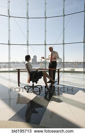 Stock Image - Business people working in large office with glass wall. Fotosearch