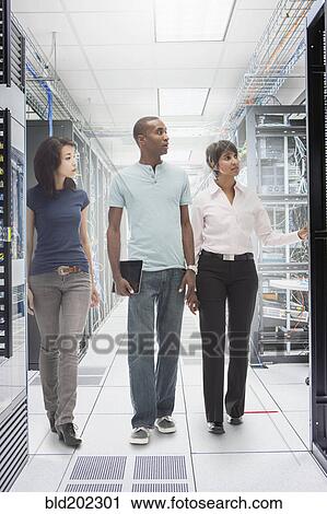 Stock Image - Business people working in server room. Fotosearch
