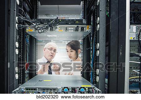 Stock Image - Business people working in server room. Fotosearch