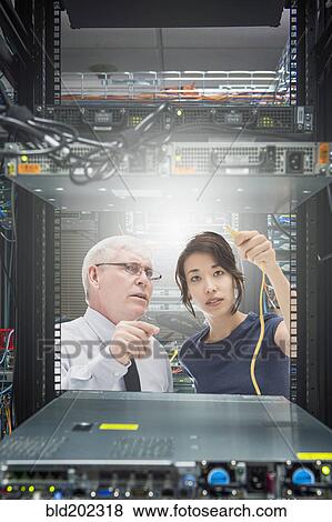 Stock Photo - Business people working in server room. Fotosearch