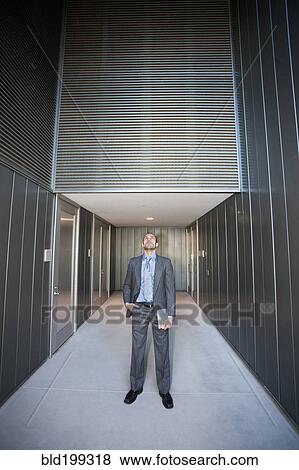 Businessman holding digital tablet in corridor View Large Photo Image Stock Photo - Businessman holding digital tablet in corridor. Fotosearch
