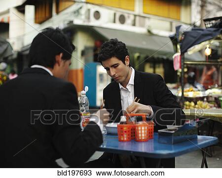 Stock Image - Businessmen eating lunch together outdoors. Fotosearch