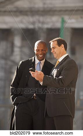 Businessmen looking at cell phone View Large Photo Image Stock Photo - Businessmen looking at cell phone. Fotosearch