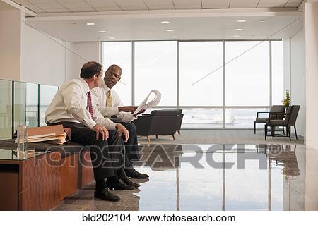 Businessmen reviewing paperwork together View Large Photo Image Picture - Businessmen reviewing paperwork together. Fotosearch
