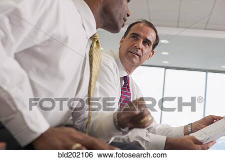 Businessmen reviewing paperwork together View Large Photo Image Stock Photograph - Businessmen reviewing paperwork together. Fotosearch