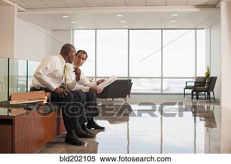 Stock Photography - Businessmen reviewing paperwork together. Fotosearch