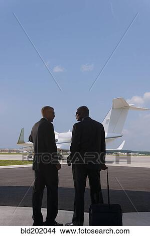 Businessmen standing on airport tarmac View Large Photo Image Picture - Businessmen standing on airport tarmac. Fotosearch