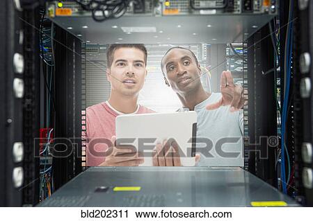 Stock Image - Businessmen working in server room. Fotosearch