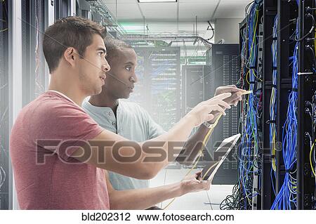 Stock Image - Businessmen working in server room. Fotosearch
