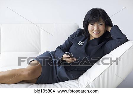 Picture - Businesswoman with feet up text messaging on cell phone. Fotosearch