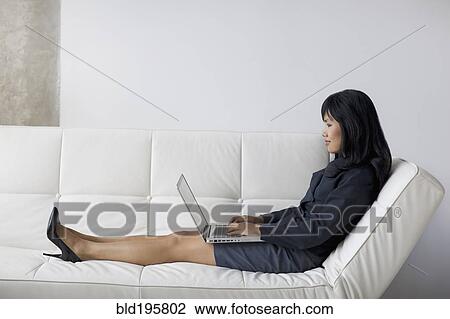 Businesswoman with feet up using laptop on sofa View Large Photo Image Stock Image - Businesswoman with feet up using laptop on sofa. Fotosearch