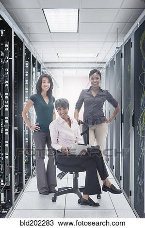 Stock Image - Businesswomen in server room. Fotosearch