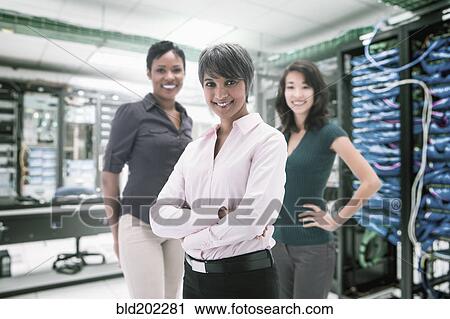 Stock Image - Businesswomen standing in server room. Fotosearch