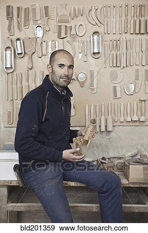 Stock Photo - Carpenter holding wood in workshop. Fotosearch