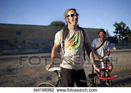 Stock Image - Caucasian bicycle messengers stopping on city street. Fotosearch