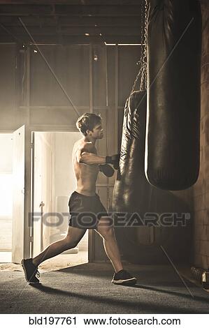 Stock Image - Caucasian boxer hitting punching bag. Fotosearch