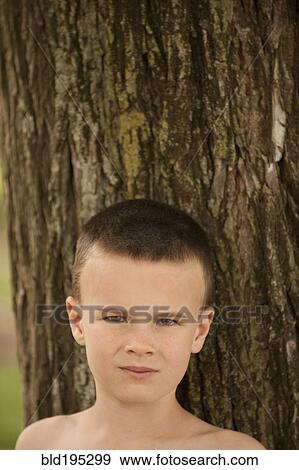 Caucasian boy leaning against tree trunk View Large Photo Image Stock Photo - Caucasian boy leaning against tree trunk. Fotosearch