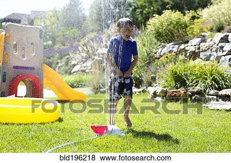 Caucasian boy playing in backyard sprinkler View Large Photo Image Stock Photo - Caucasian boy playing in backyard sprinkler. Fotosearch