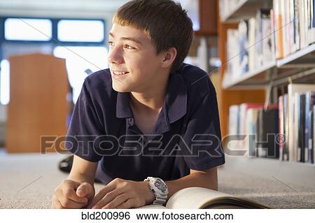 Stock Photograph - Caucasian boy reading book in library. Fotosearch