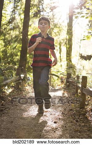 Stock Photo - Caucasian boy running on path in forest. Fotosearch