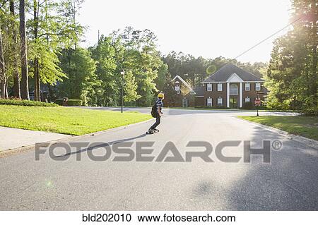 Stock Image - Caucasian boy skateboarding on road. Fotosearch