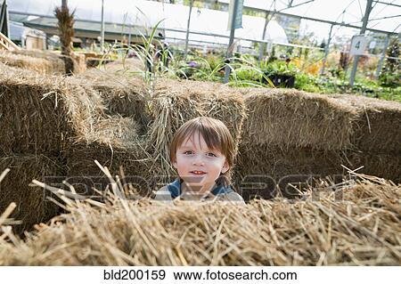 Stock Photo - Caucasian boy standing near hay bales. Fotosearch