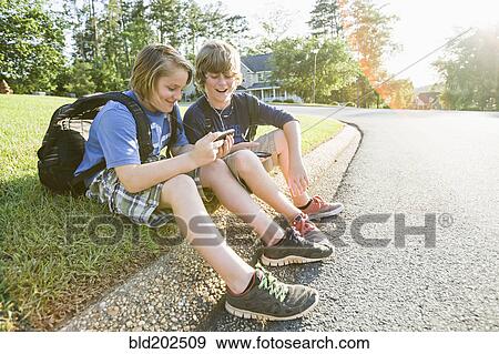 Stock Photo - Caucasian boys looking at cell phone. Fotosearch