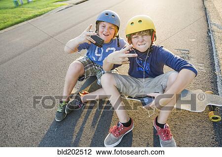Caucasian boys sitting on skateboards and making gestures View Large Photo Image Stock Image - Caucasian boys sitting on skateboards and making gestures. Fotosearch