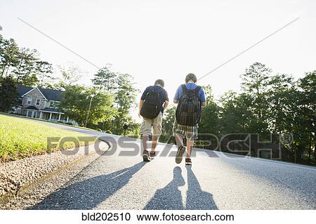 Stock Image - Caucasian boys walking in road. Fotosearch