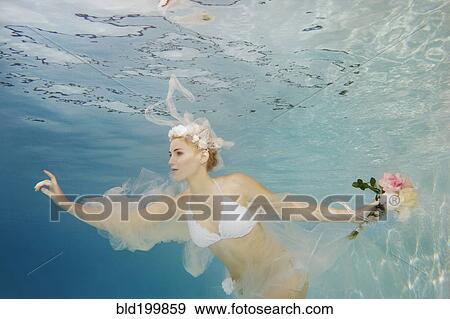 Stock Photo - Caucasian bride in bikini swimming under water. Fotosearch