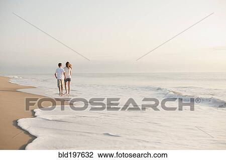 Stock Image - Caucasian brother and sister walking on beach. Fotosearch