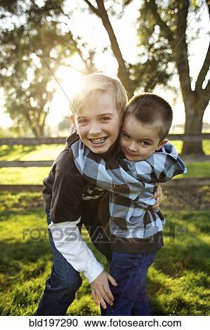 Stock Image - Caucasian brothers hugging outdoors. Fotosearch