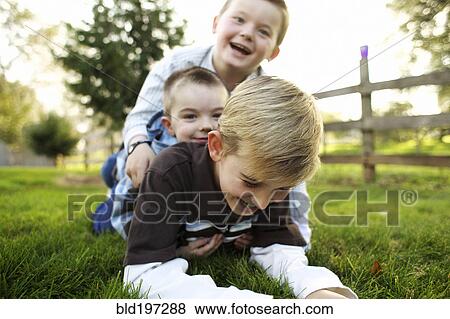 Caucasian brothers playing in grass View Large Photo Image Stock Photo - Caucasian brothers playing in grass. Fotosearch