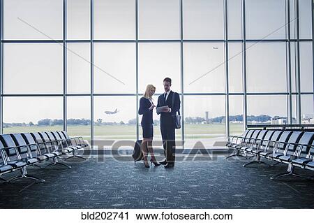 Stock Image - Caucasian business people standing in airport. Fotosearch