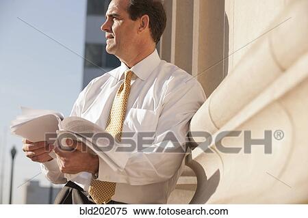 Caucasian businessman looking at paperwork outdoors View Large Photo Image Stock Photography - Caucasian businessman looking at paperwork outdoors. Fotosearch