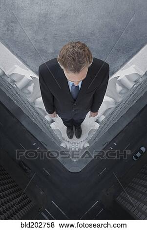 Stock Photo - Caucasian businessman on skyscraper ledge. Fotosearch