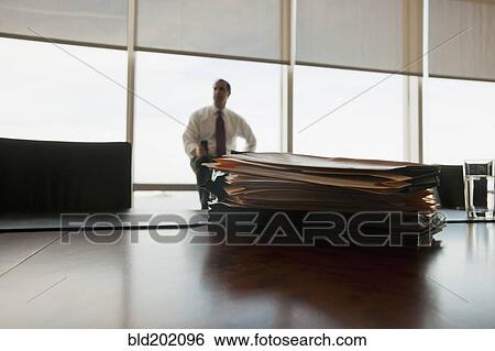 Stock Photograph - Caucasian businessman sitting behind stack of folders. Fotosearch