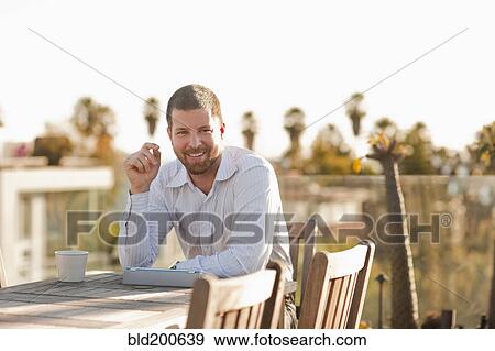 Caucasian businessman taking break on patio View Large Photo Image Stock Photo - Caucasian businessman taking break on patio. Fotosearch