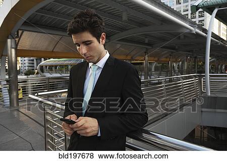 Caucasian businessman text messaging on cell phone outdoors View Large Photo Image Stock Photo - Caucasian businessman text messaging on cell phone outdoors. Fotosearch
