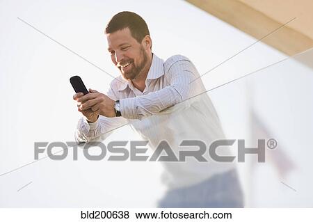 Stock Photo - Caucasian businessman text messaging on cell phone. Fotosearch