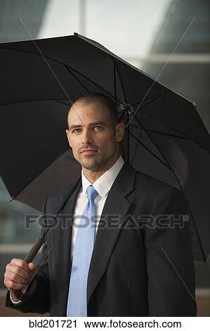 Caucasian businessman underneath umbrella View Large Photo Image Stock Image - Caucasian businessman underneath umbrella. Fotosearch