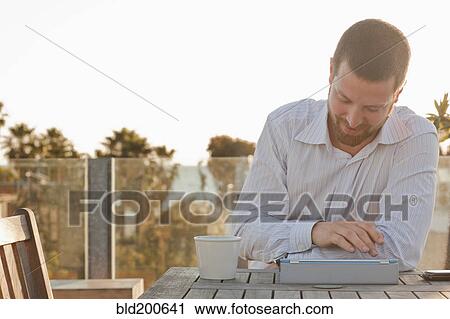 Stock Image - Caucasian businessman using digital tablet outdoors. Fotosearch