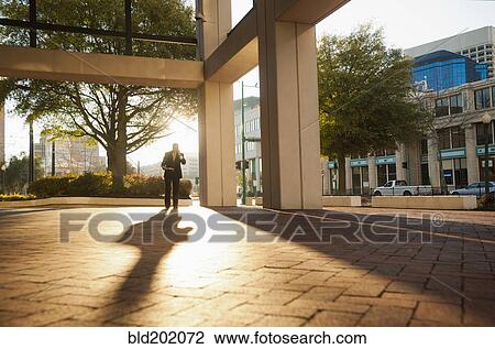 Stock Image - Caucasian businessman walking in urban area. Fotosearch