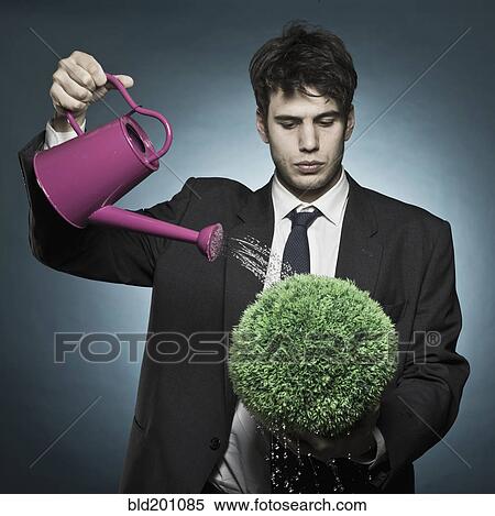 Stock Photography - Caucasian businessman watering plant. Fotosearch
