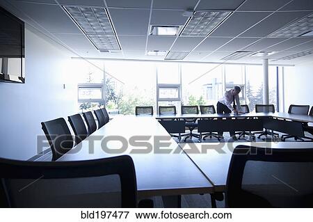 Stock Photo - Caucasian businessman working in empty conference room. Fotosearch
