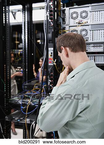 Stock Image - Caucasian businessman working in server room. Fotosearch